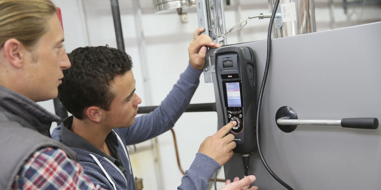 Zwei Anlagenmechaniker die eine Anlage mit einem Messgerät prüfen